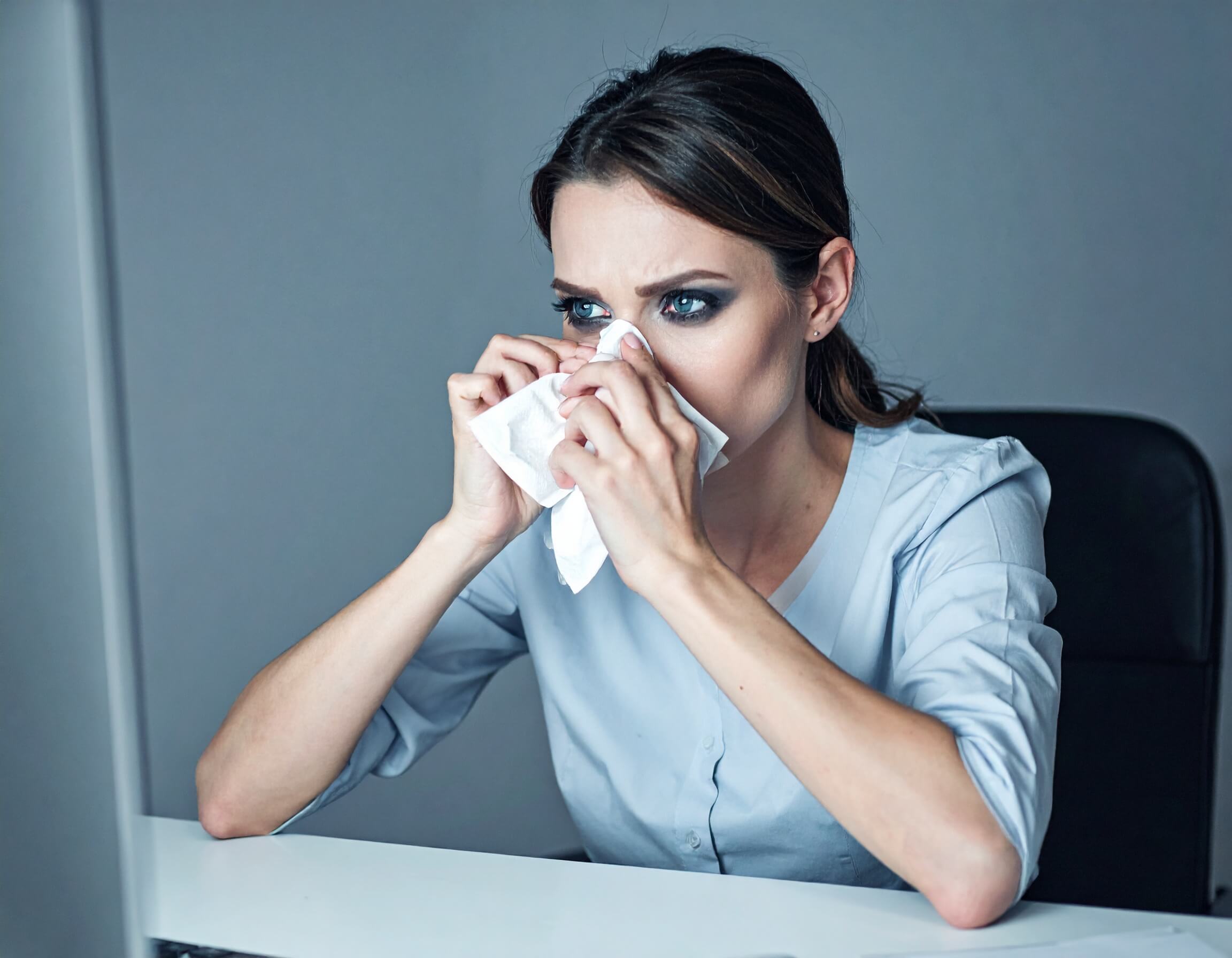sick woman at work, blowing her nose, needs disinfectant